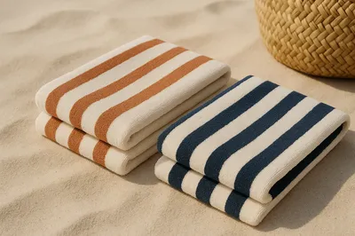 Striped wholesale beach towels folded on the sand